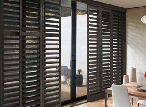 Modern room with wooden shutters and sliding glass door.