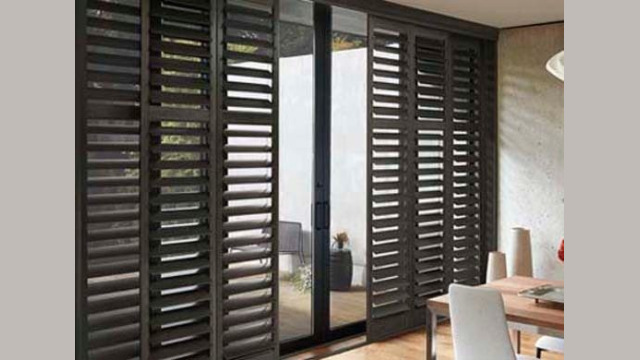 Modern room with wooden shutters and sliding glass door.