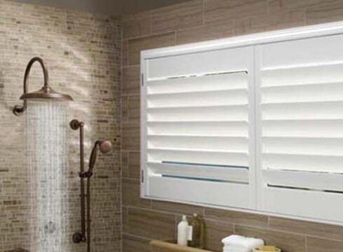 Modern bathroom with shower and window shutters.